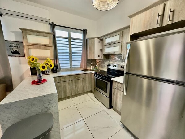 Een koelkast met diepvriezer, een microgolfoven, een oven, een kookplaat