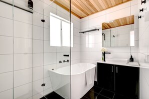 A modern bathroom with a glass shower enclosure, a freestanding bathtub, and a black vanity with a mirror. - Meadows Farmhouse - Adelaide Hills (Meadows)