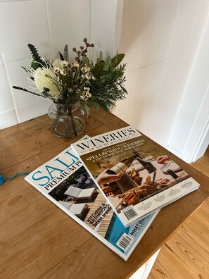 A magazine titled 'WINTER' on a wooden table, with a vase of flowers in the background. - Meadows Farmhouse - Adelaide Hills (Meadows)