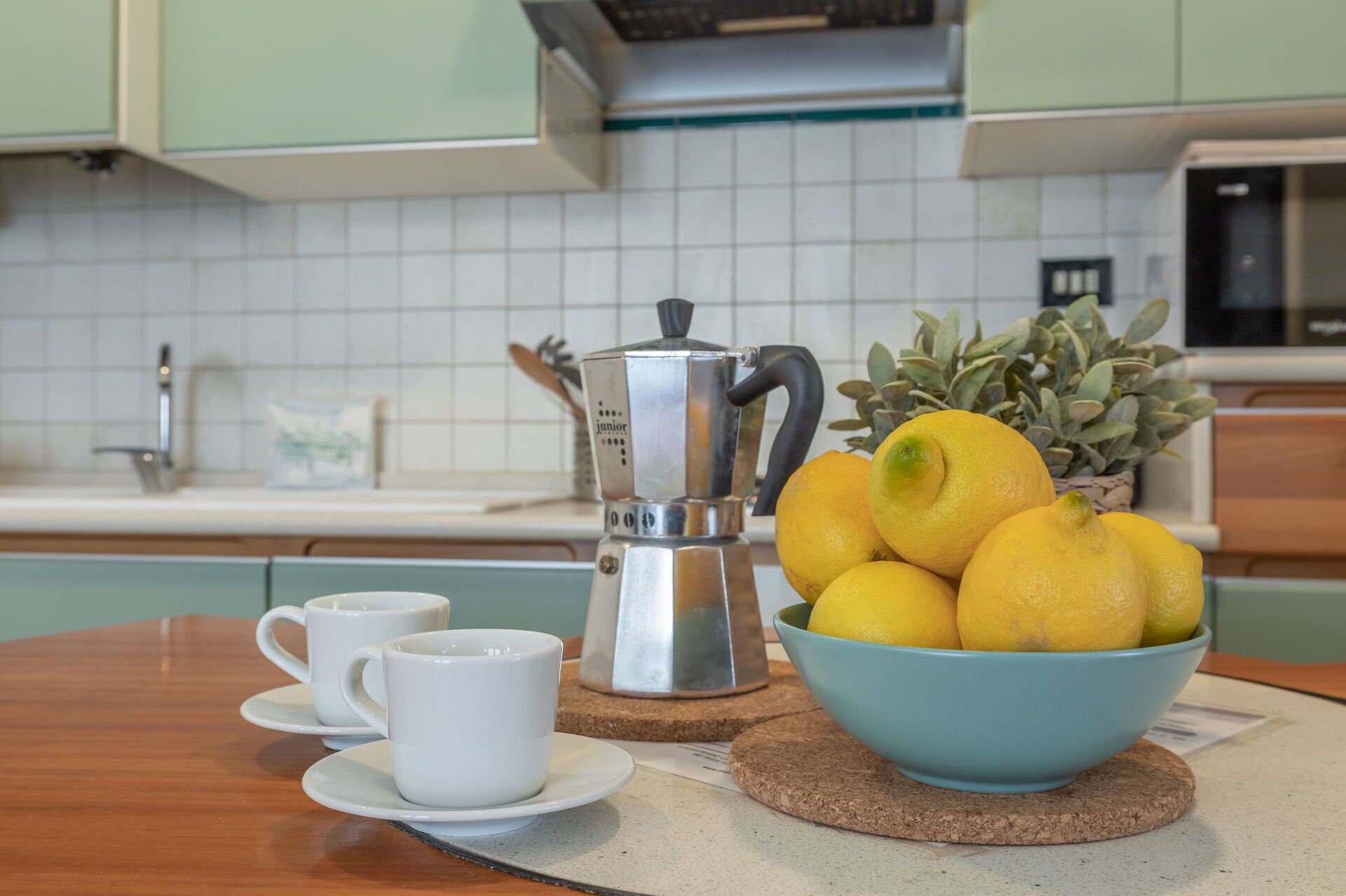 Eine Küche mit Kaffeemaschine, einer Zitronenschale und zwei weißen Tassen auf einem Tisch.