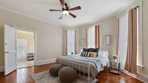 A bedroom with a bed, a ceiling fan, a nightstand, and a window with curtains.