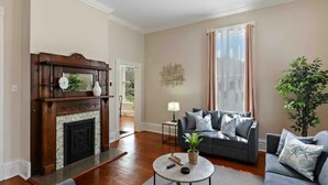 A living room with a fireplace, a sofa, a coffee table, and a large window with curtains.