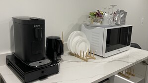Een keuken met een koffiezetapparaat, magnetron en afwassysteem.