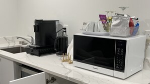 Een keuken met een magnetron, koffiezetapparaat en een afwasschuur.