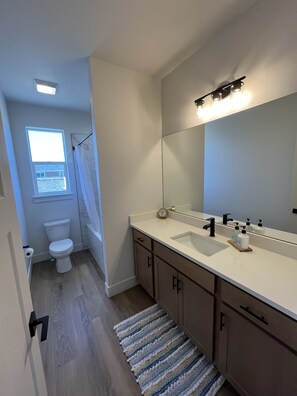 A modern bathroom with a toilet, sink, and mirror.