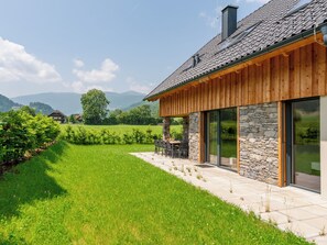 A modern house with a stone facade, wooden exterior, and a patio with outdoor seating. - Luxurious house with sauna (Kreischberg)
