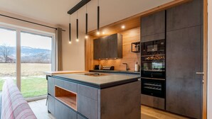 Een moderne keuken met een groot eiland, inbouwapparatuur en uitzicht op de omgeving.