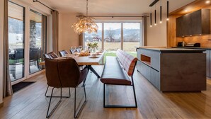 Een moderne keuken met een eethoek, grote ramen en uitzicht op de omgeving.