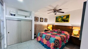 A bedroom with a bed, a ceiling fan, a nightstand with a lamp, and a wall-mounted air conditioner. - Meson del capitan 8 depa en el centro! (Mazatlán)