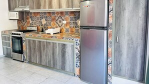 A kitchen with wooden cabinets, a stainless steel refrigerator, a microwave, and a stove. - Meson del capitan 8 depa en el centro! (Mazatlán)