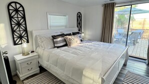 Een ruime slaapkamer met een groot bed, nachtkastje, raam en uitzicht op het landschap.