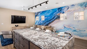 A modern kitchen with a marble island, a large TV, and a marble backsplash. - Pet-friendly! Near downtown Oceanside - Sea Spray (Oceanside)