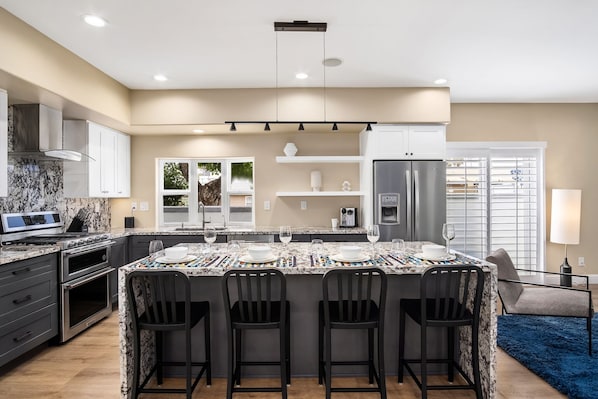 A modern kitchen with a large island, built-in oven, and stainless steel appliances.