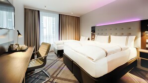 A hotel room with a large bed, a desk with a chair, a TV, and a bedside table. - Premier Inn Hamburg City Klostertor (Hamburg)