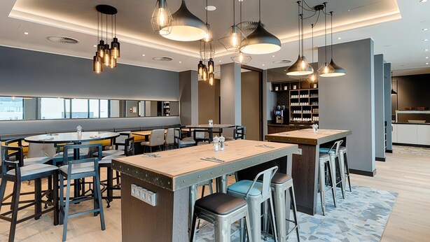 A modern bar area with multiple seating options, pendant lighting, and a visible bar counter. - Premier Inn Hamburg City Klostertor (Hamburg)