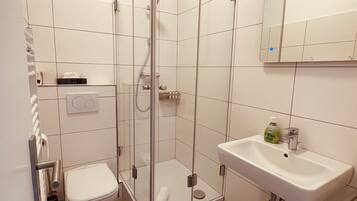Une salle de bain moderne avec une douche à parois de verre, un lavabo blanc et des toilettes.