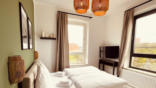 A bedroom with a bed, a television, and a window with a view. - Fährhaus Kirschenland (Jork)