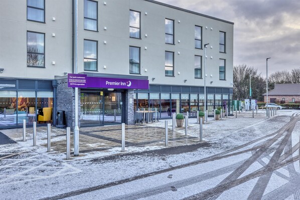 A hotel with a modern facade, a car park sign, and a CCTV notice.