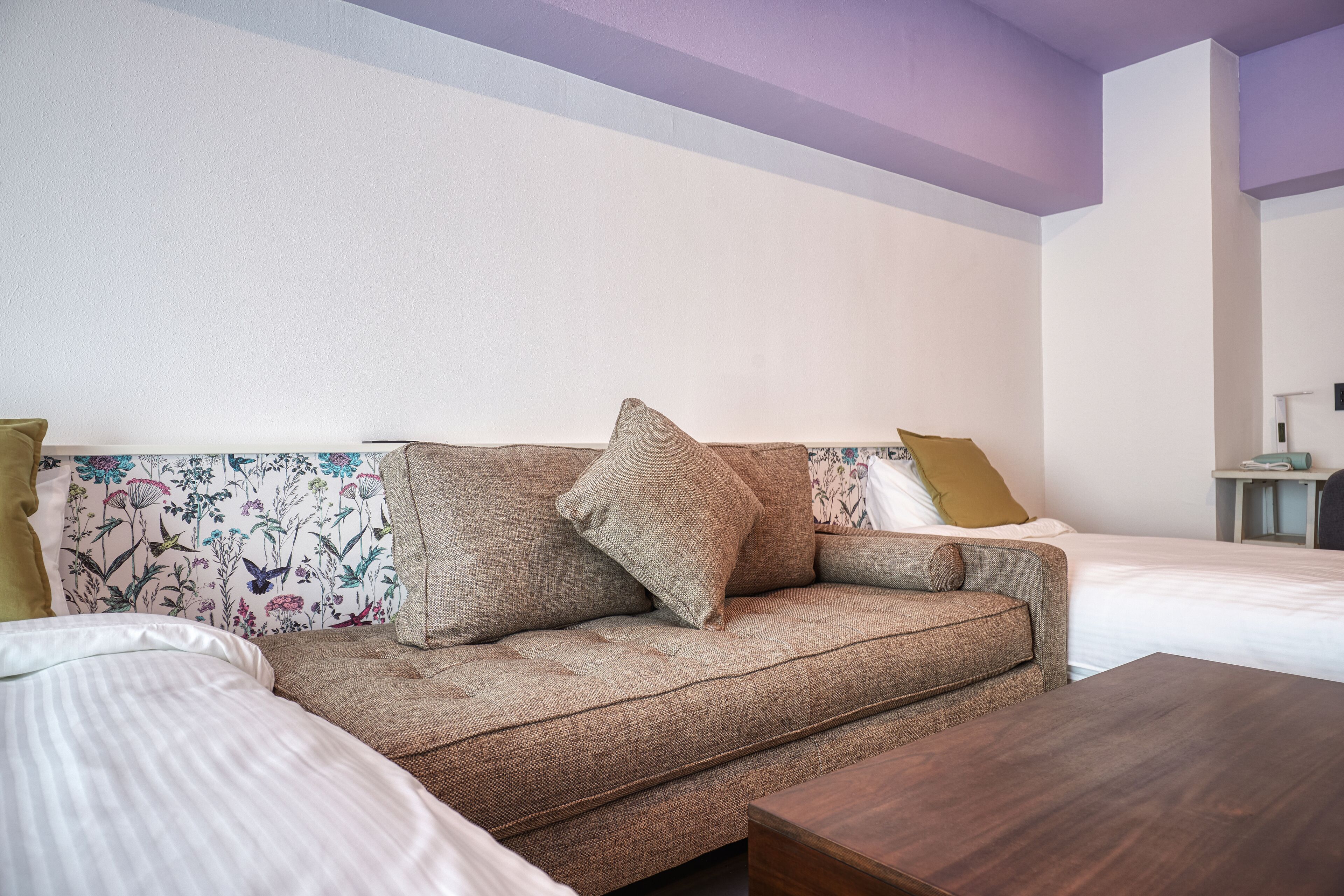 A room with a sofa, a wooden coffee table, and a bed with white bedding.