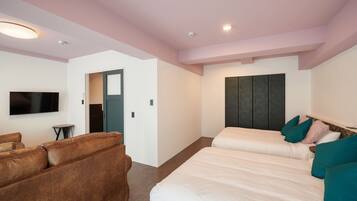 A modern hotel room with a large bed, a sofa, a flat-screen TV, and a wardrobe.