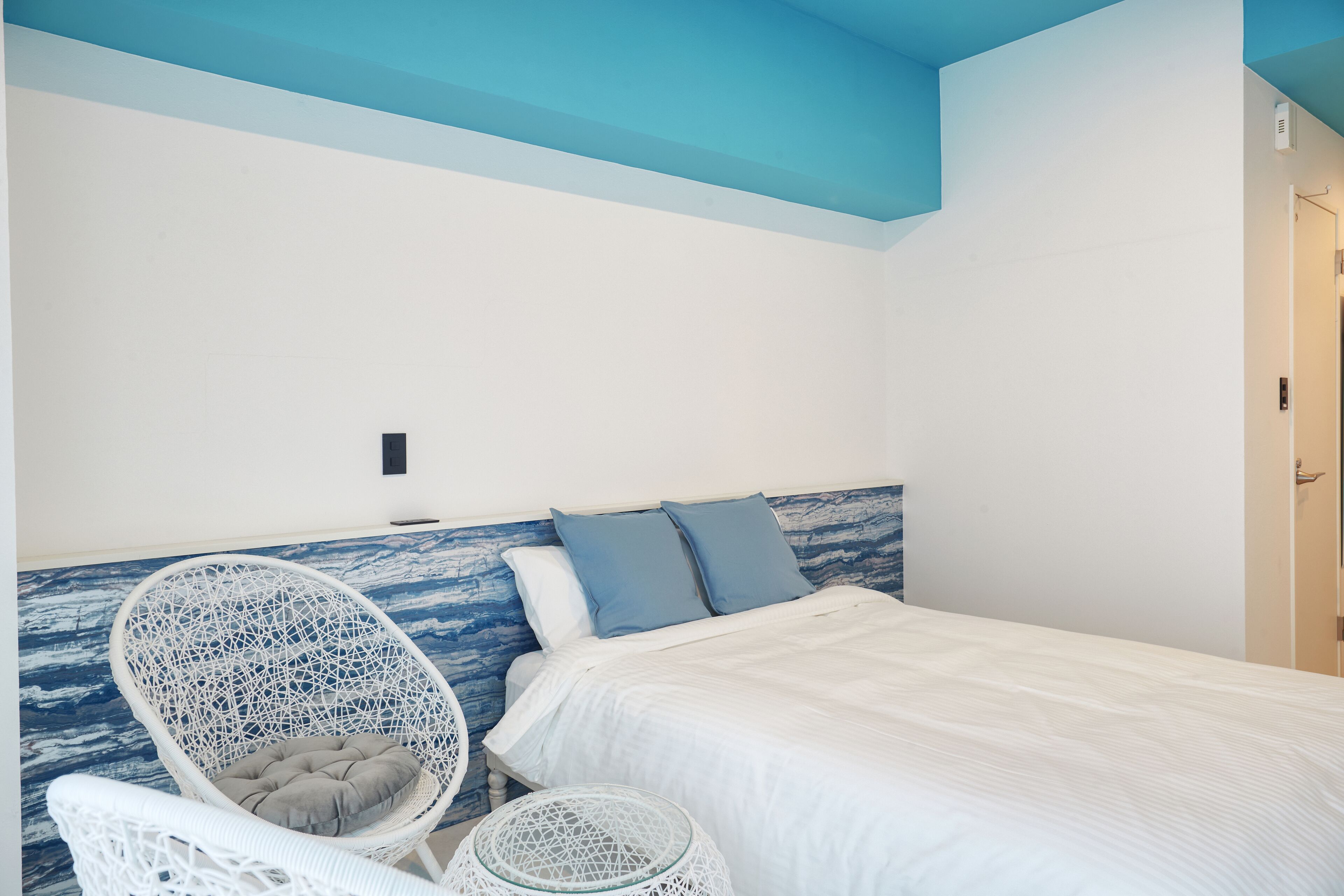 Una camera da letto con un letto, due cuscini, una sedia bianca e un tavolino rotondo.