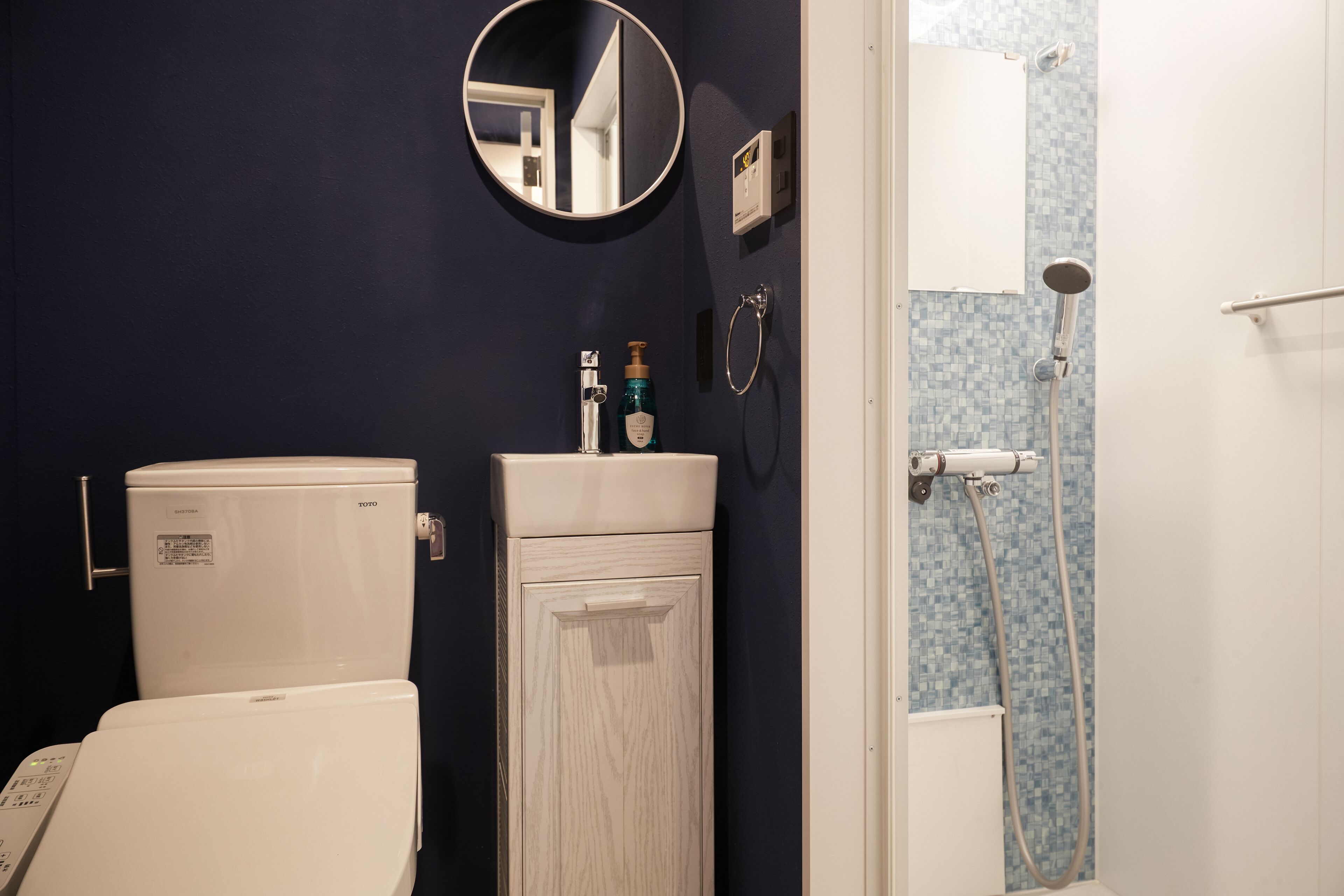 A bathroom with a toilet, sink, mirror, and shower.
