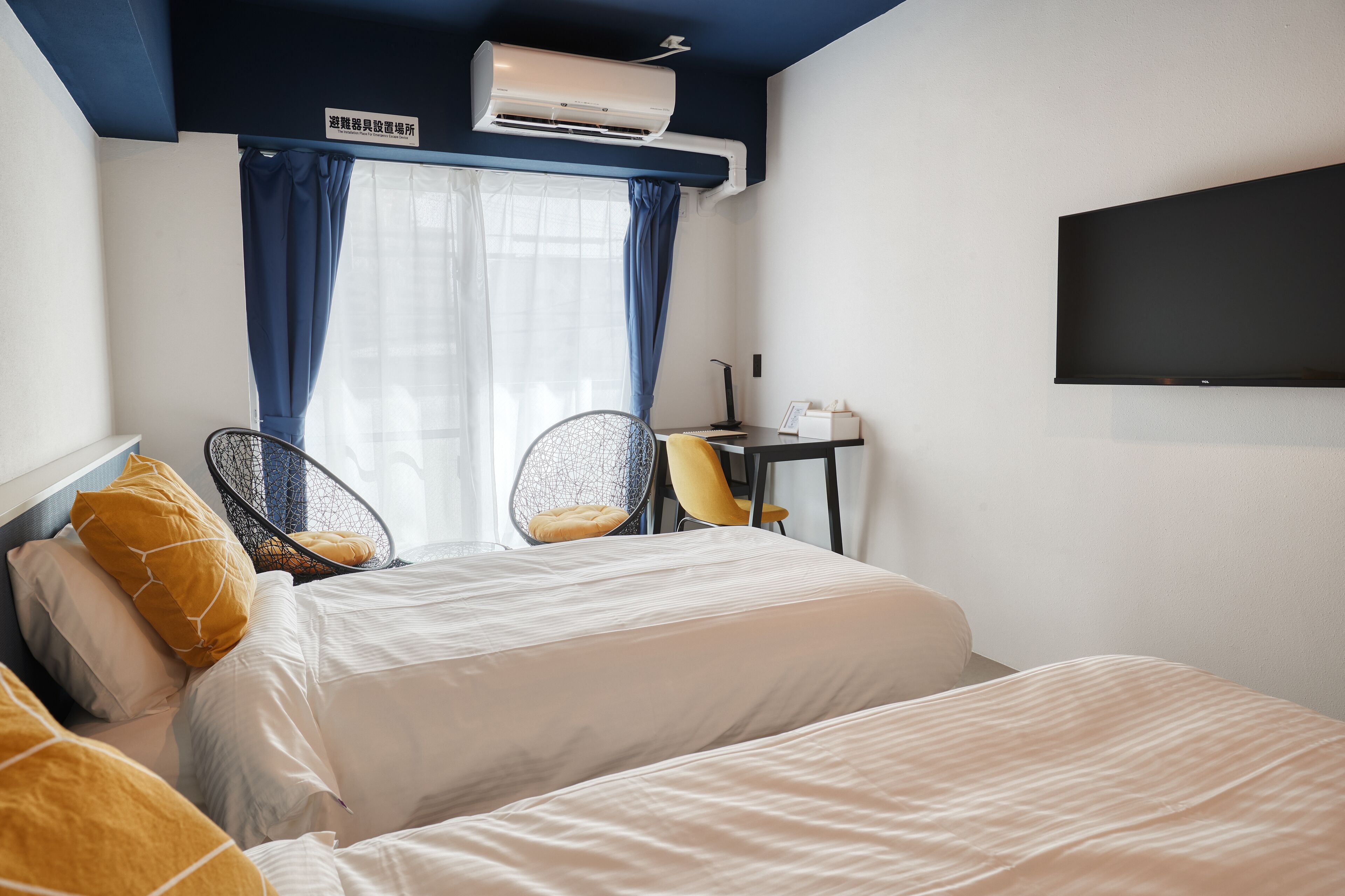 A hotel room with a bed, two chairs, a desk, and a flat-screen TV.