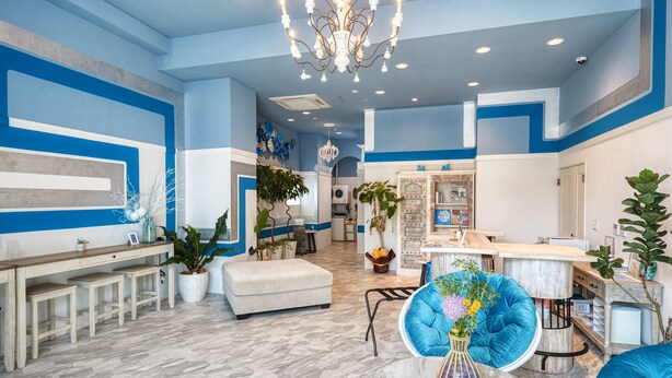 Ein modernes Interieur mit blau-weißer Farbgestaltung, einer Chandelüster und einer Sitzecke mit einem Marmortisch.