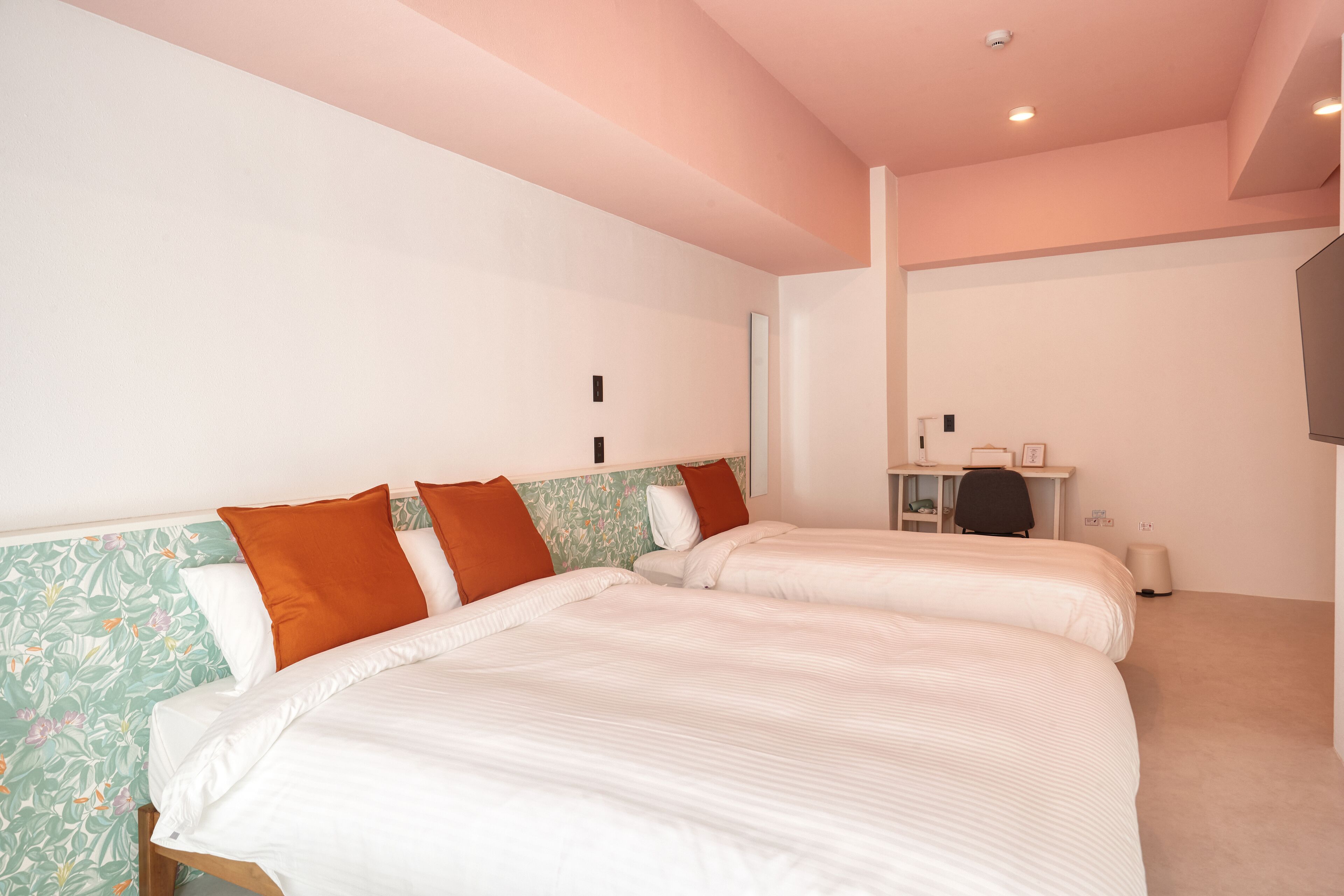 Habitación de hotel con dos camas, un escritorio y una televisión.