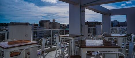 An outdoor terrace with tables and chairs, offering a view of the cityscape.