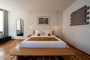 A modern hotel room with a wooden bed, a large mirror, and a wall-mounted artwork. - 4BR Luxury Modern Contemporary Villa in Canggu (Canggu)