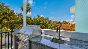 Una cucina esterna con una griglia, un lavello e vista sulla piscina.