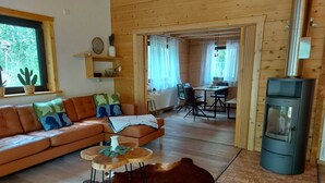 Un salon chaleureux avec un canapé en cuir, une table basse et un tapis en peau de vache. On y trouve également un coin repas avec une table et des chaises, ainsi qu’une cuisine équipée d’une cuisinière.