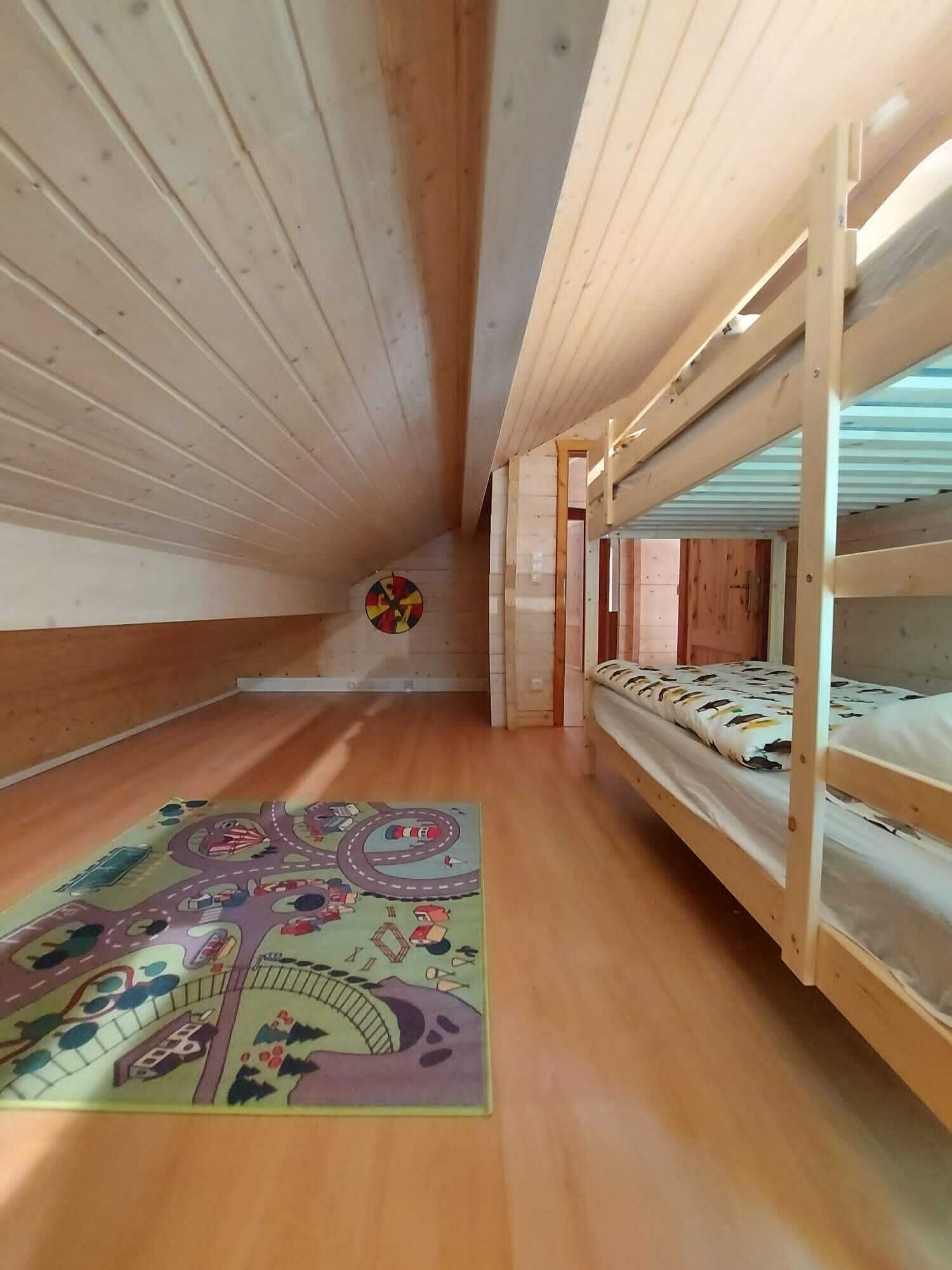 A bunk bed room with wooden walls and a colorful rug on the floor.