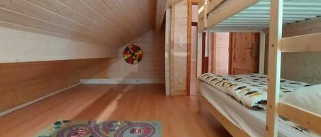 A bunk bed room with wooden walls and a colorful rug on the floor.