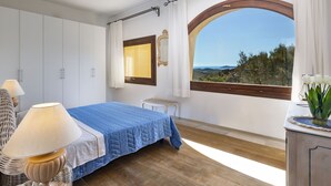 Un dormitorio con cama, ventana con vistas, lámpara y cómoda.