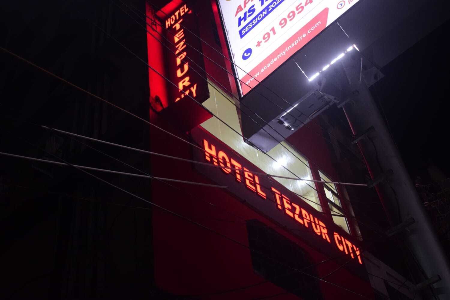 A hotel sign with the name "HOTEL TEZPUR CITY" in bright orange letters.