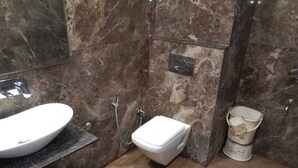 A bathroom with a white sink, a toilet, and a trash bin.