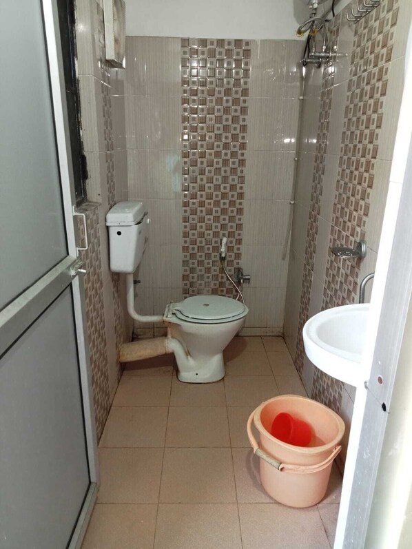 A small bathroom with a toilet, a shower, and a sink.