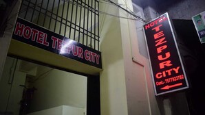 A hotel sign with the name "HOTEL TEZPUR CITY" and a contact number.