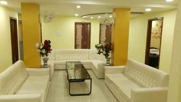 A living room with white sofas, a glass coffee table, and two flower vases.