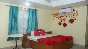 A bedroom with a bed, a small table, curtains, and wall decorations.