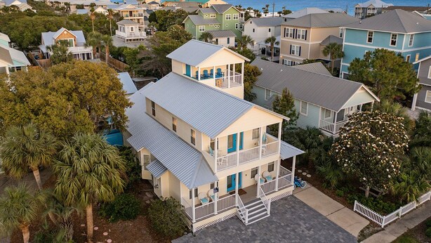 A coastal residential area with houses featuring balconies and front porches, surrounded by trees and a view of the ocean. - Flirty Flamingo- Pet-Friendly Vacation Home Near Beach with Private Pool Area (Destin)
