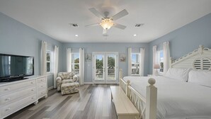 A bedroom with a bed, a television, a bench, a chair, and a ceiling fan. - Flirty Flamingo- Pet-Friendly Vacation Home Near Beach with Private Pool Area (Destin)