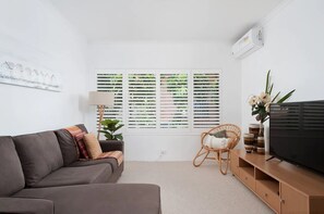 Relax in this stylish living room with a sofa, side table, and wicker chair.