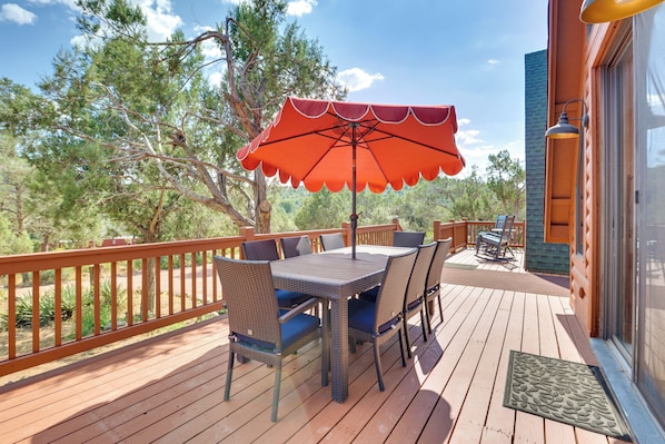 A wooden deck with a table and chairs, an umbrella, and a view of trees. - Hot Tub & Mtn View: Dog-Friendly Payson Getaway! (Payson)