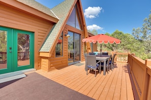 A wooden cabin with a deck, a dining area with outdoor furniture, and a red umbrella. - Hot Tub & Mtn View: Dog-Friendly Payson Getaway! (Payson)