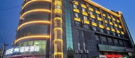 A multi-story hotel with a modern design, featuring a curved facade and illuminated vertical lines.