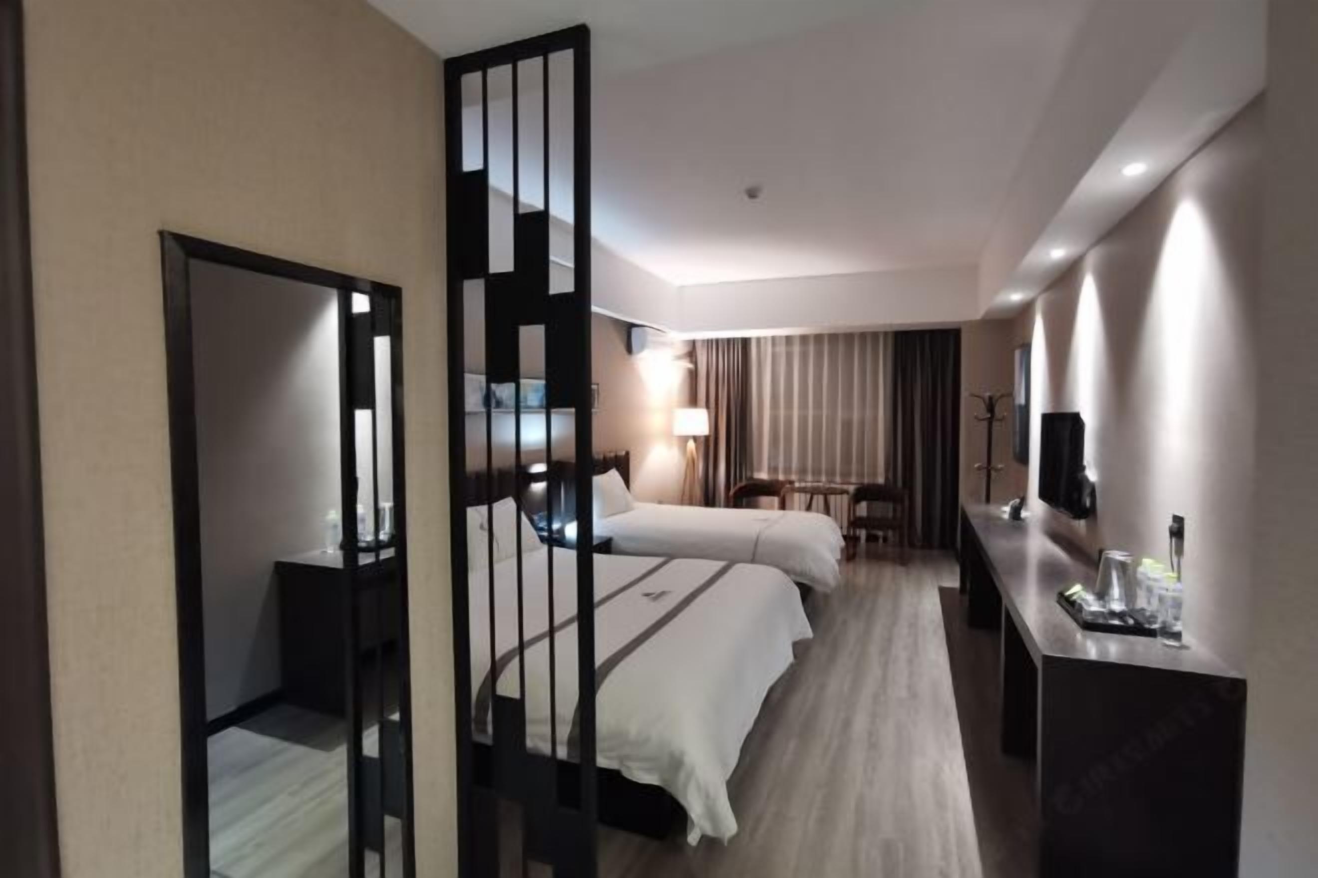Een hotelkamer met twee bedden, een bureau met spiegel, een stoel en een tafeltje met spullen erop.