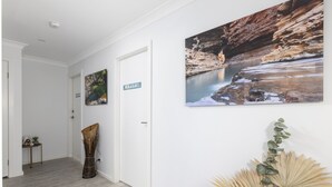 A hallway with a wooden floor, a door, and a wall with a 'WHALE' sign and two framed pictures.